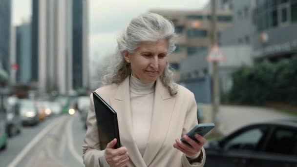 Зрелая деловая женщина ходит с планшетом и мобильным телефоном — стоковое видео