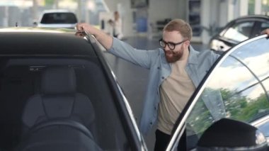 Lviv, Ukrayna - 21 Mayıs 2021: Lüks arabanın yanında duran ve iç mekanı inceleyen olumlu adam