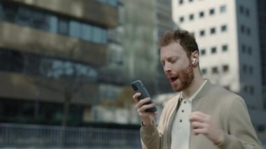 Müzik dinlemek için kulaklık ve akıllı telefon kullanan mutlu adam.