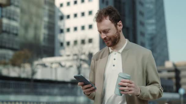 Kaukasier läuft auf Straße und tippt Nachricht auf Handy — Stockvideo