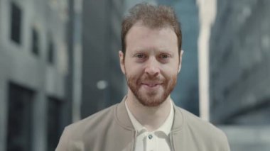 Ofis binasının yanında şık giyinmiş bir işadamı duruyor.