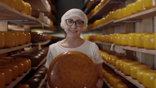 Female expert standing at storage with cheese head in hands — 图库视频影像