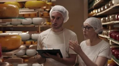 İki mandıra işçisi peynir kafalarını kontrol ediyor.