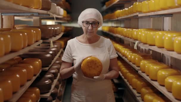 Tecnologista feminina segurando cabeça de queijo na fábrica de laticínios — Vídeo de Stock