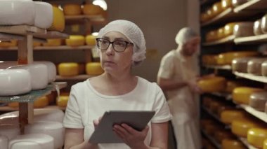 Kadın ve erkek peynir fabrikasında tablet kullanıyor.