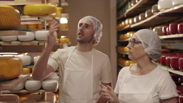 Мужчина и женщина осматривают молочные продукты на складе — стоковое видео