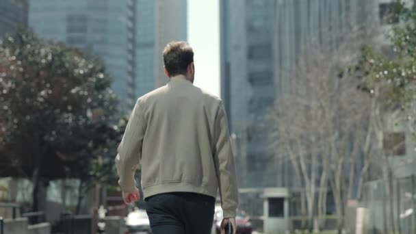 Back view of man in casual smart clothes walking on street — 비디오