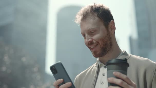 Man using mobile while standing outdoors with cup of coffee — Video