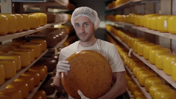 Young man holding cheese wheel while standing at farm house — стоковое видео