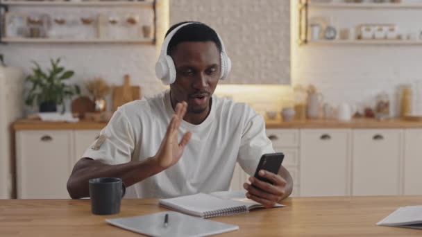 African guy using smartphone and headphones for video lesson — ストック動画