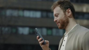 Beyaz adamın sokakta akıllı telefon kullanışının yan görüntüsü