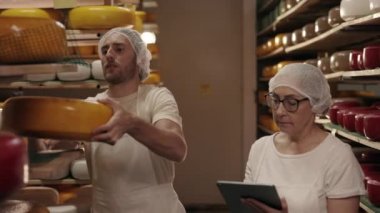 Kadın tablet üzerinde çalışırken, adam peynir kafasını kontrol ediyor.