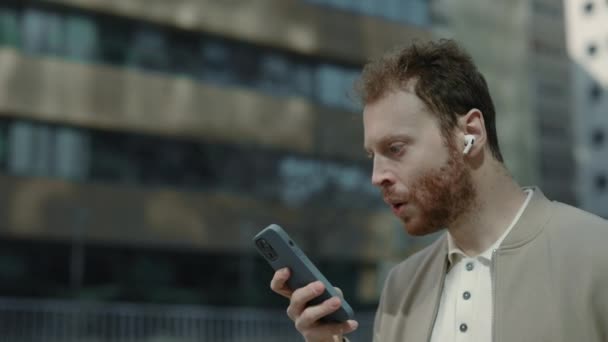 Hombre sorprendido leyendo algunas buenas noticias en el teléfono inteligente — Vídeos de Stock