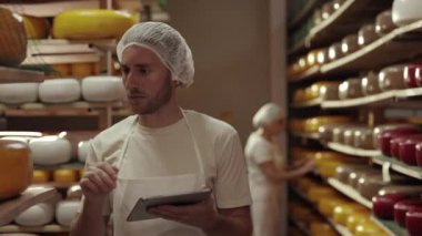 Olgunlaşan peynir kafalarını kontrol eden iki meslektaş