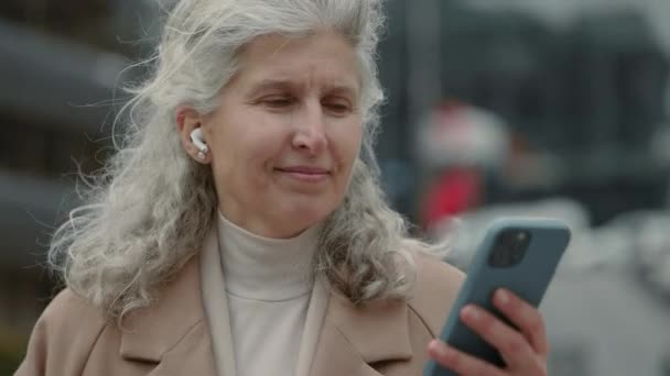 Mujer mayor usando auriculares y móviles para escuchar música — Vídeo de stock