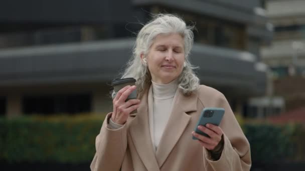 Idős nő használ fülhallgató és mobil hallgat dalt — Stock videók