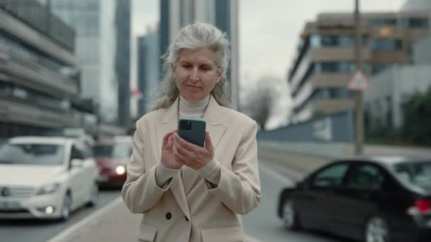 Envejecida mujer de negocios caucásica utilizando móvil al aire libre — Vídeos de Stock