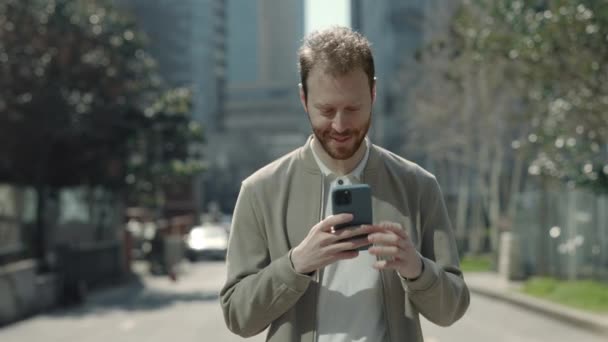 Красивый человек просматривает интернет на улице на смартфоне — стоковое видео