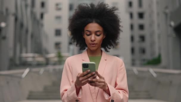 Boas notícias. Retrato de mulher de negócios feliz desfrutar de sucesso no smartphone andando perto do centro de escritório. Feminino comemorando vitória com telefone. — Vídeo de Stock