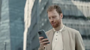 Dışarıda akıllı telefondan mesaj yazmakla meşgul genç adam.