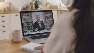 Öğretim üyesiyle video dersi için dizüstü bilgisayar kullanan öğrenci