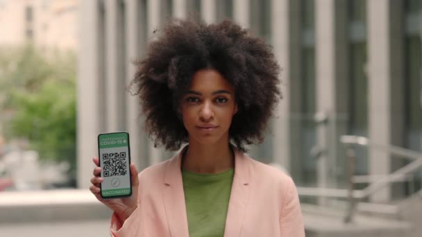 Retrato de mujer de negocios mostrando su teléfono inteligente con el código qr pasaporte digital para covid-19 de pie limpio centro de negocios. Está vacunada. — Vídeo de stock