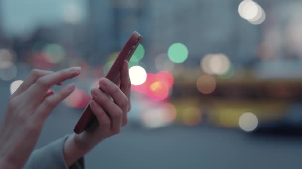 Cerca de teléfono inteligente moderno en manos femeninas sobre la ciudad de la noche — Vídeo de stock