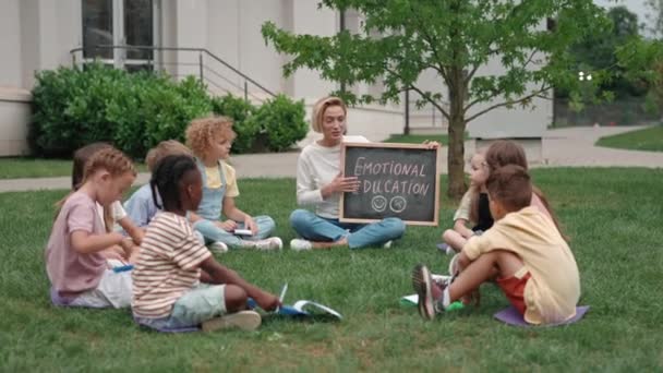 Niños en edad escolar que tienen lecciones sobre emociones humanas al aire libre — Vídeo de stock