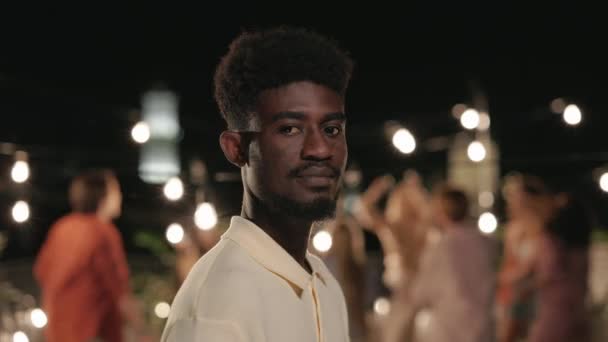Afro-Typ lächelt während einer Party mit Freunden auf dem Dach in die Kamera — Stockvideo