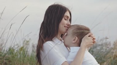 Şefkatli anne sahada oğlunu kucaklıyor ve öpüyor.