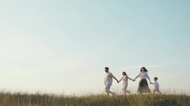 Vacker familj på fyra promenader tillsammans bland fält — Stockvideo