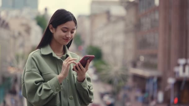 Asiatico donna holding cell phone mentre standing all aperto — Video Stock