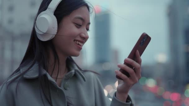 Mujer en auriculares desplazándose con el dedo en la pantalla móvil — Vídeos de Stock