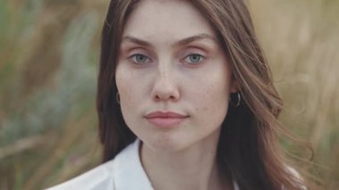 Yaz tarlasında poz veren doğal güzelliği olan muhteşem genç bir kadının portresi. Kameraya bakan yeşil gözlü hoş bir esmer. Kırsal alan.