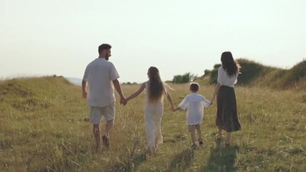 Kaukasische vierköpfige Familie hält Händchen und geht in der Natur spazieren — Stockvideo