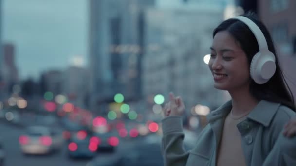 Aziatische vrouw dansen op straat in draadloze hoofdtelefoon — Stockvideo