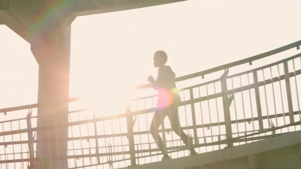 Kulaklıklı aktif Afrikalı kadın köprüde koşuyor. — Stok video