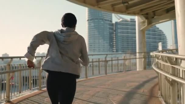O femeie africană îmbrăcată în haine sport, alergând dimineața în oraș — Videoclip de stoc