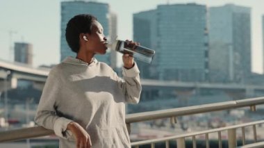 Genç Afrikalı kadın sabah koşusundan sonra su içiyor.