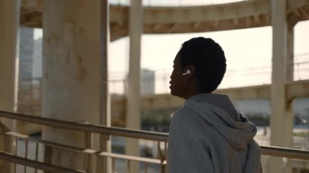 Ajuste mujer africana en auriculares inalámbricos corriendo al aire libre — Vídeos de Stock