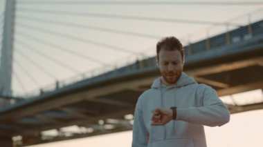 Erkek koşucu kulaklık ve spor takip cihazı kullanıyor.