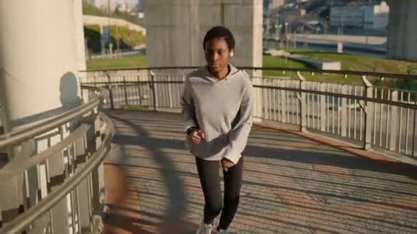Африканская женщина бегает одна по городскому мосту — стоковое видео