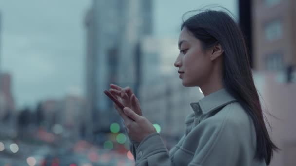 Asian woman walking on city street with smartphone in hands — Stock Video