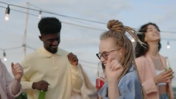 Woman with dreads relaxing with diverse friends on rooftop — Stock Video