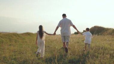 Tatlı baba iki küçük çocukla yaz tarlasında yürüyor.