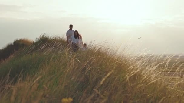 Zwei Kinder mit Eltern bei sonnigem Wetter auf dem Hügel — Stockvideo