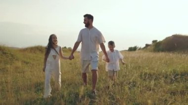 Baba oğul ve kız yaz tarlasında yürüyorlar.