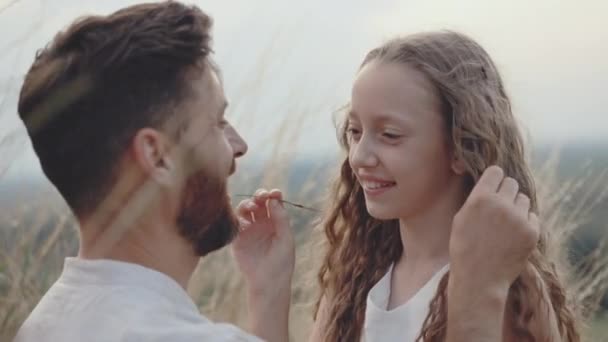 Позитивна дівчина грає зі своїм дбайливим батьком на літньому полі — стокове відео
