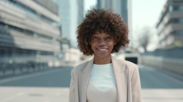 Mujer africana sonriente posando cerca del centro de negocios — Vídeos de Stock