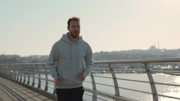 Homme fort en vêtements de sport courant sur le pont de la ville — Video